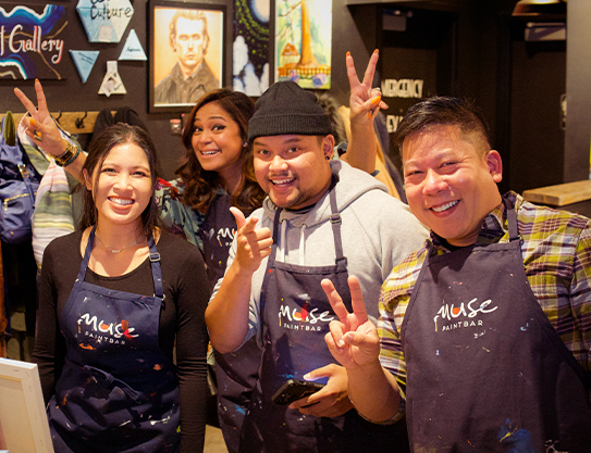 Young adult friends posing in Muse aprons